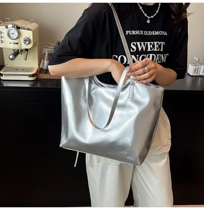 Detail of silver metallic tote bag with faux leather texture and long handles for commute