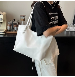 Detail of white large capacity tote bag with silver metal buckles and slim shoulder straps