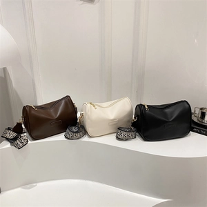 Three retro cylindrical crossbody bags in brown, white and black with patterned straps