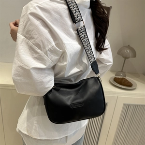 Minimalist black leather crossbody bag with stylish geometric patterned wide shoulder strap