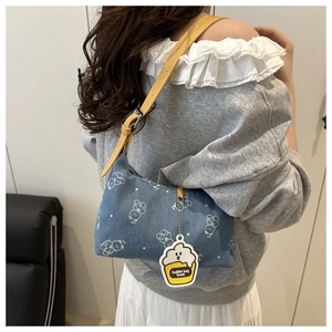 Detail of blue denim shoulder bag with white bear prints and yellow leather strap