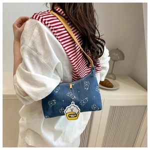Detail of blue denim shoulder bag with white bear prints and cupcake charm