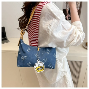 Close-up of denim shoulder bag featuring white bear prints and a fashion bag charm
