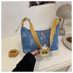Detail of blue denim bag featuring white bear prints and yellow leather strap accents