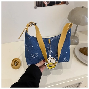 Close-up of blue denim hobo bag with white cartoon bear prints and yellow leather straps
