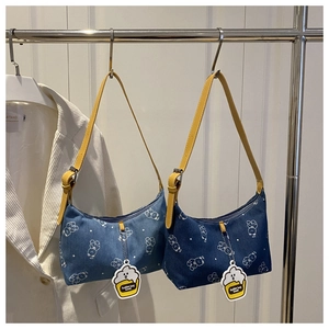Detailed view of denim underarm bags with bear print and yellow adjustable straps