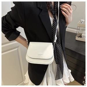 Minimalist white saddle bag shown with a black blazer and white pleated skirt