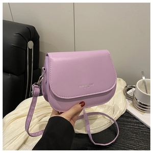 Detail of lavender leather saddle bag with silver lettering in a stylish cafe setting