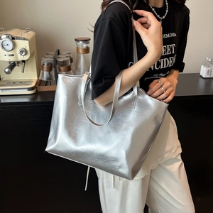 Metallic silver large capacity tote bag worn by a model in a modern café setting