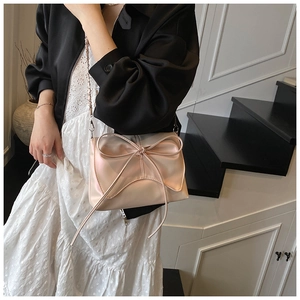 Détail du sac sous l'aisselle plissé rose champagne avec un grand nœud et une bandoulière