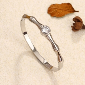 Silver bamboo joint bangle with a large sparkling round diamond placed on a beige textured base