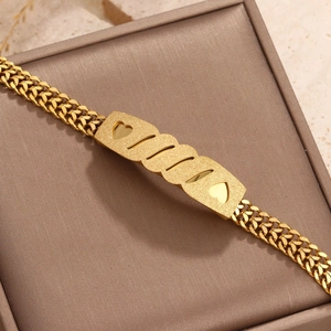 Macro shot of gold stainless steel bracelet with matte heart plaque on leather box