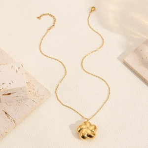 Elegant gold five-petal flower pendant necklace displayed on a textured marble block