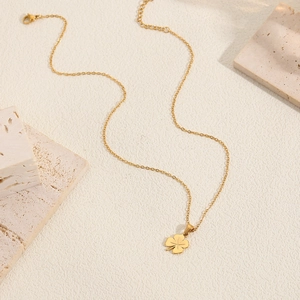 Élégant collier avec pendentif trèfle doré sur pierre de travertin beige minimaliste