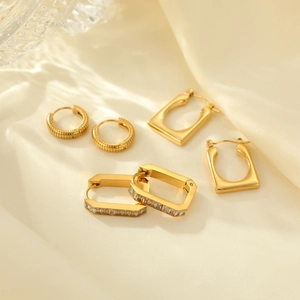 Three pairs of elegant gold-plated stainless steel geometric earrings on silk background