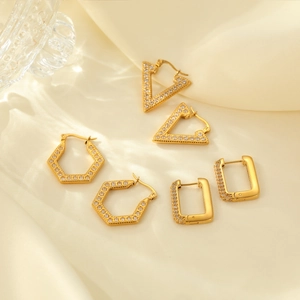 Minimalist gold geometric earring set with cubic zirconia on a soft beige fabric background
