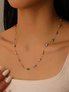 Macro shot of colorful faceted water-drop beads on a delicate golden chain necklace