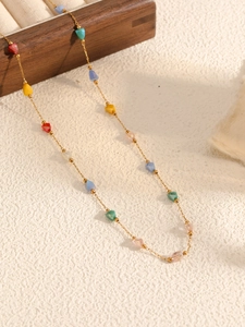 Detailed close-up of a gold chain necklace with colorful faceted crystal beads on wood