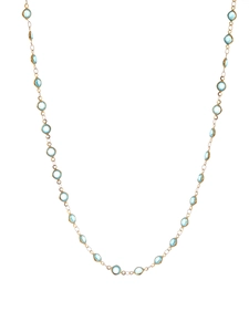 Detail of gold chain necklace with bezel-set light blue round crystals in macro view