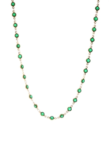 Detail of gold chain necklace featuring bezel-set green round faceted gemstones