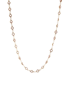 Detail of elegant gold chain necklace with bezel-set champagne gemstones on white backdrop