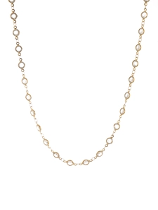 Macro detail of gold plated long chain necklace with bezel-set clear crystal stones