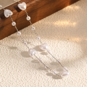 Collier de perles avec perles en cœur et chaîne argentée pour femme sur fond texturé