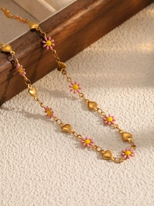 Détail d'un collier doré avec marguerites en émail rose et plaques en métal en cœur