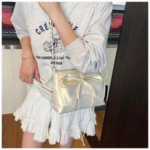 Détail du sac à bandoulière blanc crème avec nœud élégant et texture nacrée raffinée