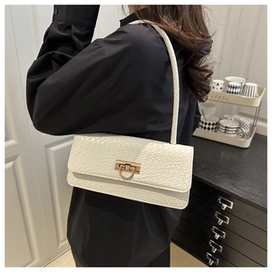 Détail du sac baguette blanc à motif crocodile avec fermoir doré porté à l'épaule
