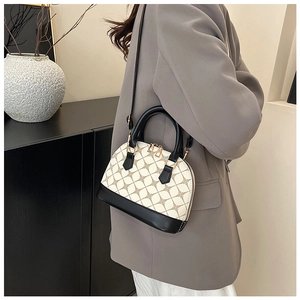 Detail of shell-shaped crossbody bag with beige geometric floral pattern and black leather