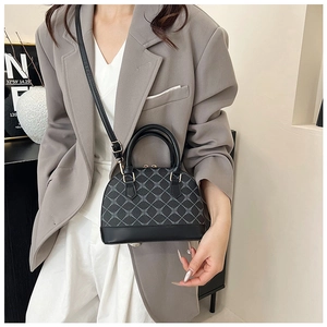Detail of shell handbag with crossbody strap, worn with grey blazer and white trousers