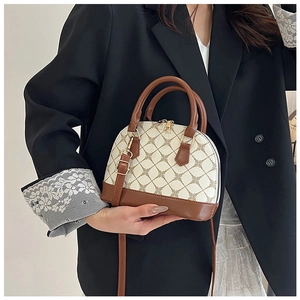 Detail of vintage shell-shaped crossbody bag featuring cream monogram and brown leather trim