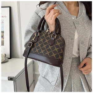 Detail of a brown shell handbag with gold chain print and adjustable shoulder strap