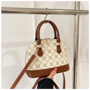 Close-up of contrast color shell bag showing brown geometric pattern and gold hardware