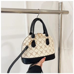 Close-up of shell-shaped crossbody bag with monogram print and black leather contrast