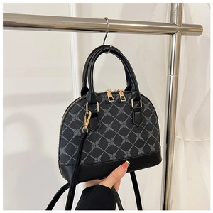 Detail view of black shell bag with grey diamond patterns and golden dual zippers
