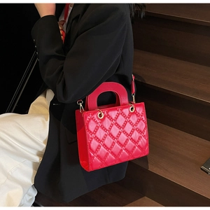 Dettaglio di una borsa trapuntata rossa con occhielli in metallo tenuta da una modella