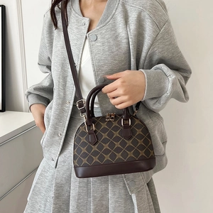 Vintage dark brown shell bag with geometric monogram and adjustable strap worn by model