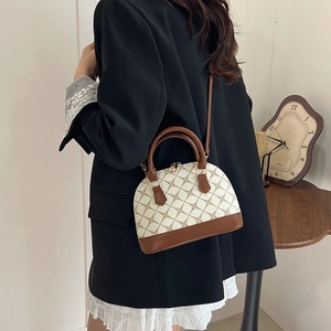 Vintage shell-shaped handbag with monogram print and brown leather trim on a model