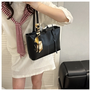 Detail of black leather tote bag with white contrast stitching and a printed silk scarf
