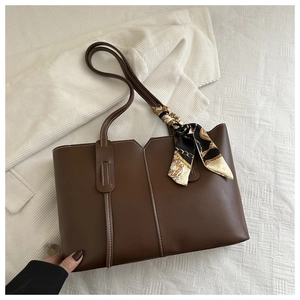 Detail of dark brown tote bag featuring contrast stitching and a decorative silk scarf