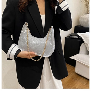 Silver snakeskin bag with gold chain strap held by a model in modern interior