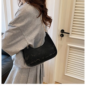 Detailed side view of black snake-pattern crescent bag with gold chain on model