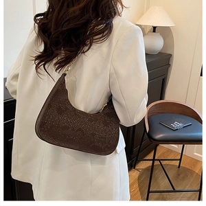Detail of dark brown snakeskin embossed underarm bag with elegant gold chain strap