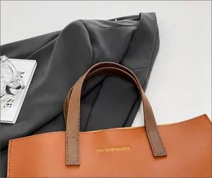 Detalle de las cómodas asas y costuras en un bolso tote de cuero marrón para mujer