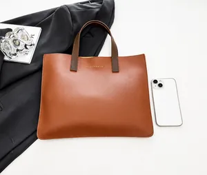 Vista plana del bolso tote de cuero marrón con texto dorado y móvil de referencia