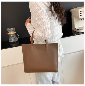 Detalle de bolso tote marrón café en cuero PU mate con elegante logo dorado