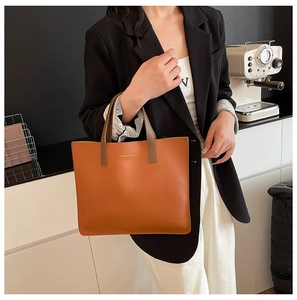Detalle del bolso tote de cuero marrón con logotipo llevado por una modelo en el hogar