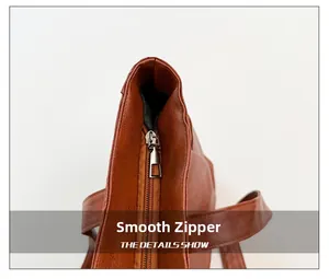 Detail of smooth metal zipper and textured brown leather on the tote bag's top closure